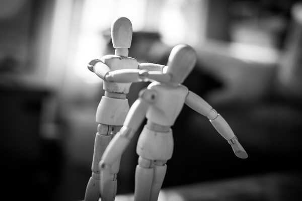 Dois bonecos de madeira onde um boneco está a estrangular o outro representando violência domestica 